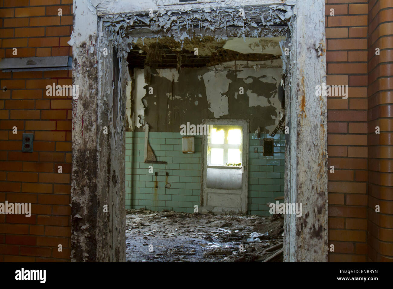 Paint peeling and chipping off doorway of room filled with debris from a decaying building. Stock Photo