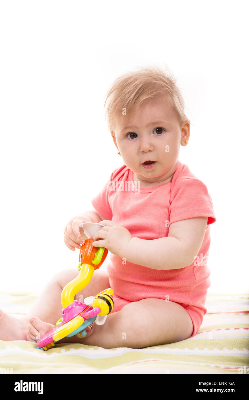 Cute blond baby girl playing with toys and sitting on blanket Stock Photo