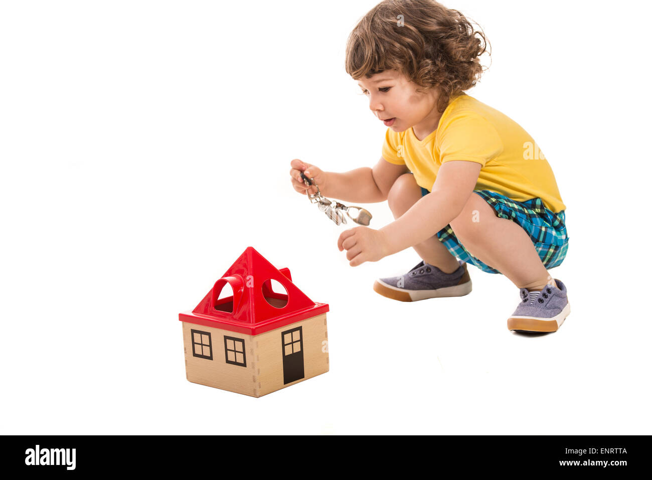 Little boy holding keys  to open  wooden house toy isolated on white background Stock Photo