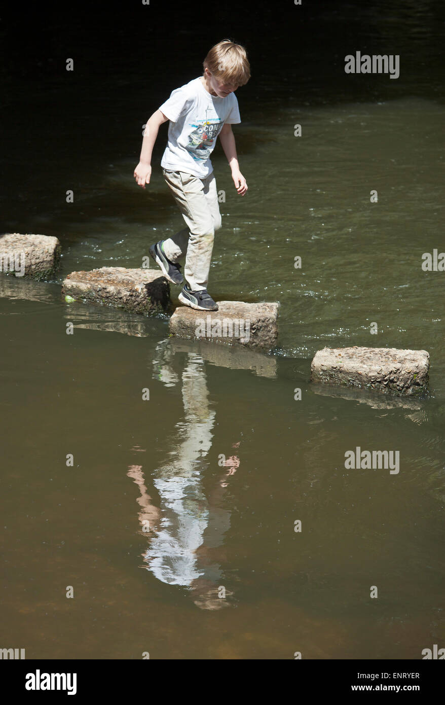 Boy jumping across stepping stones. Stock Photo
