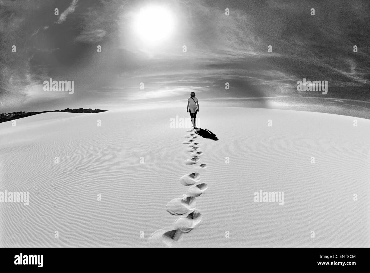 Portugal, Algarve: woman walking on a sand dune in direction of the sun in black and white Stock Photo