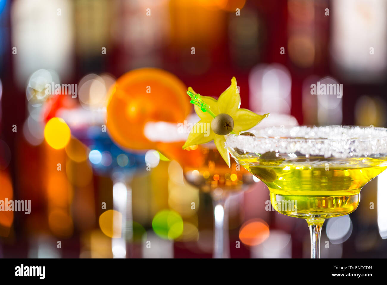 Martini drinks served on bar counter with blur bottles on background