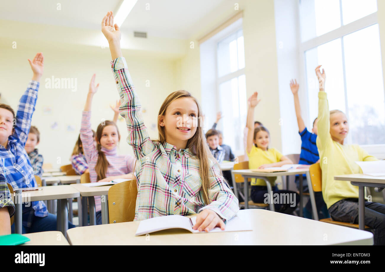 group of school kids raising hands in classroom Stock Photo Alamy