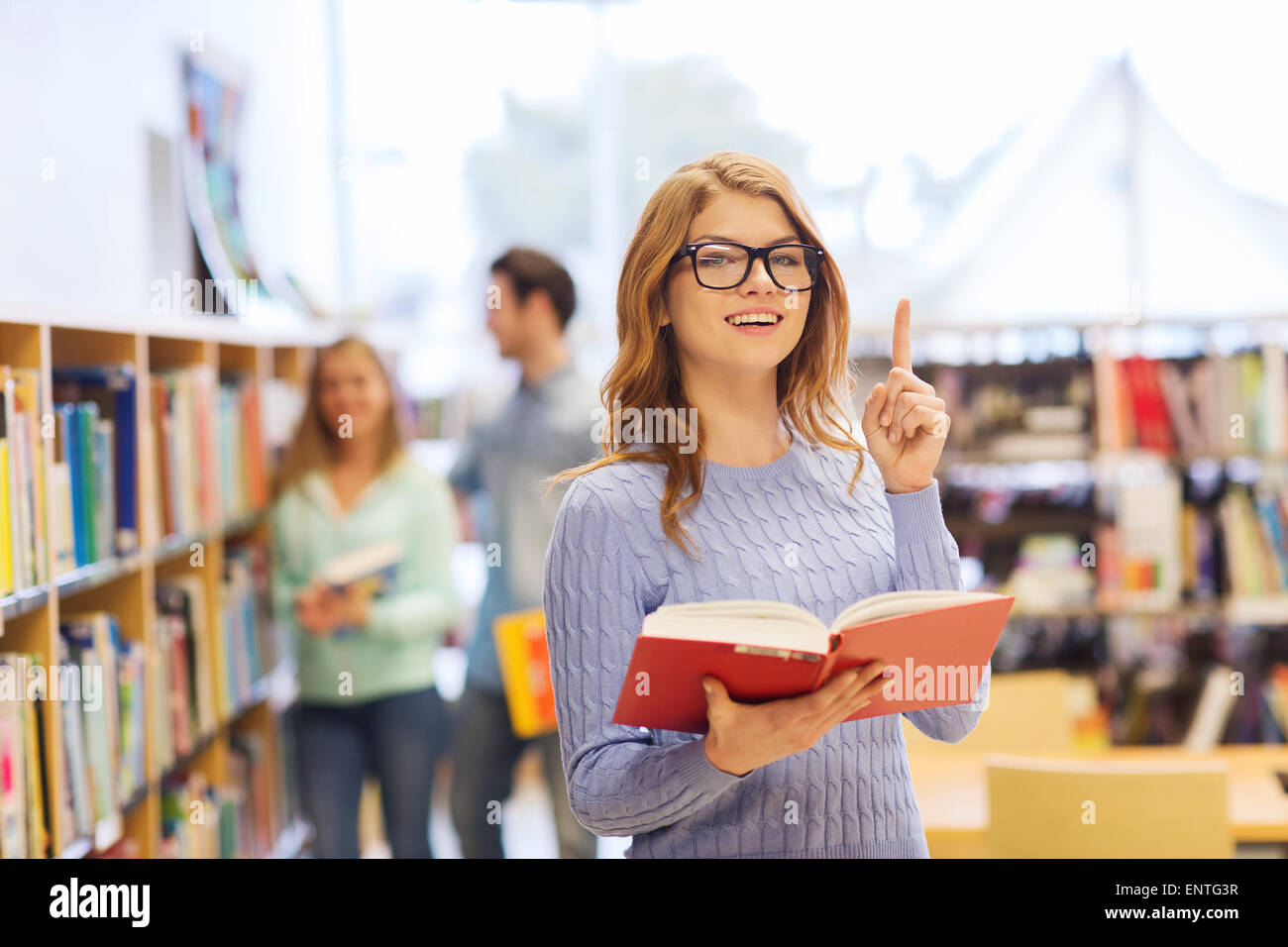 happy student girl or woman with book in library Stock Photo - Alamy