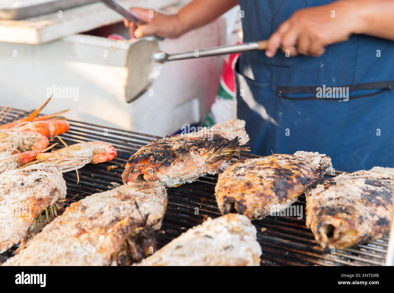 close up of cook hands grilling fish on street Stock Photo
