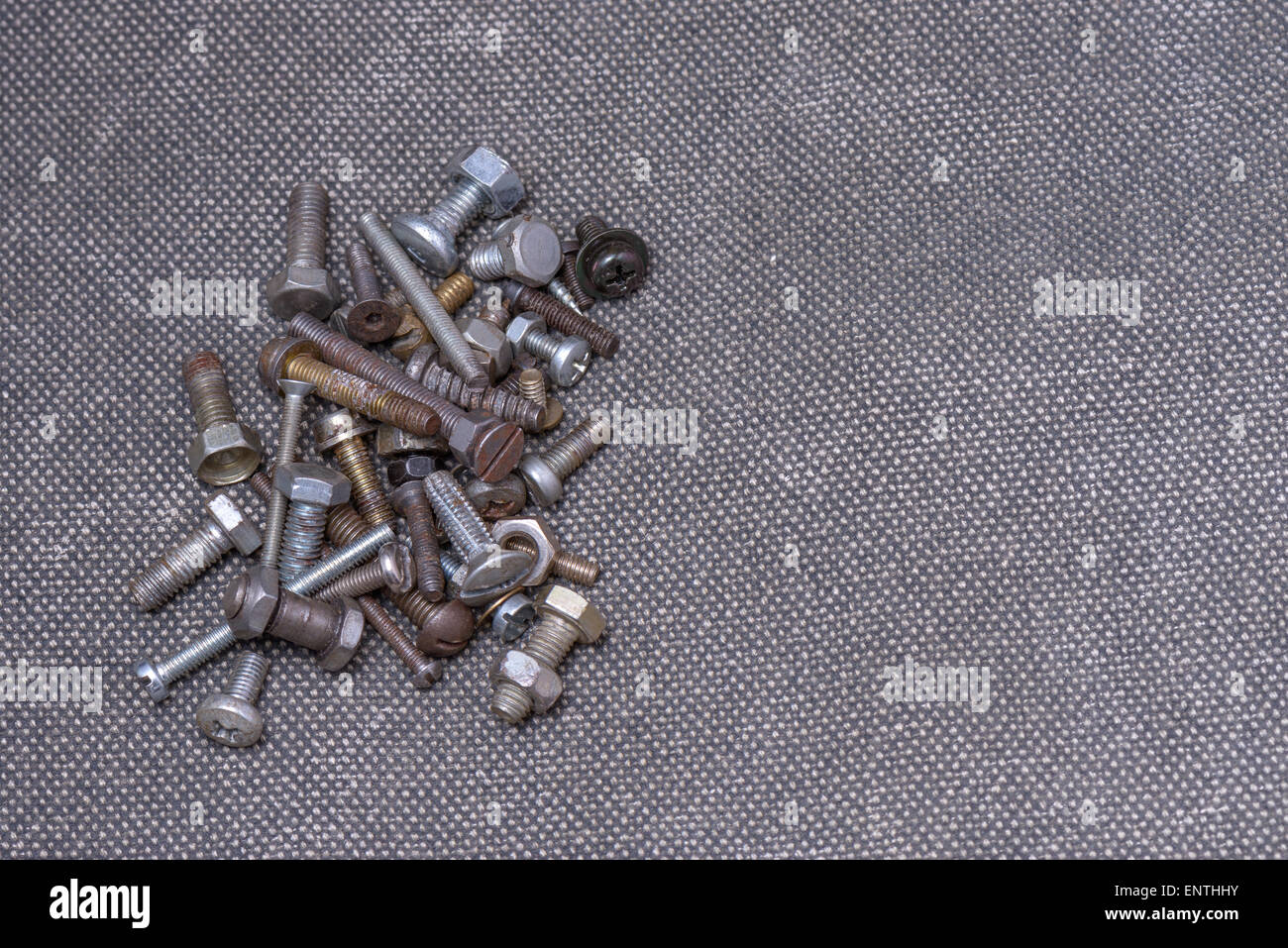 Several old screws on a grey texile background Stock Photo