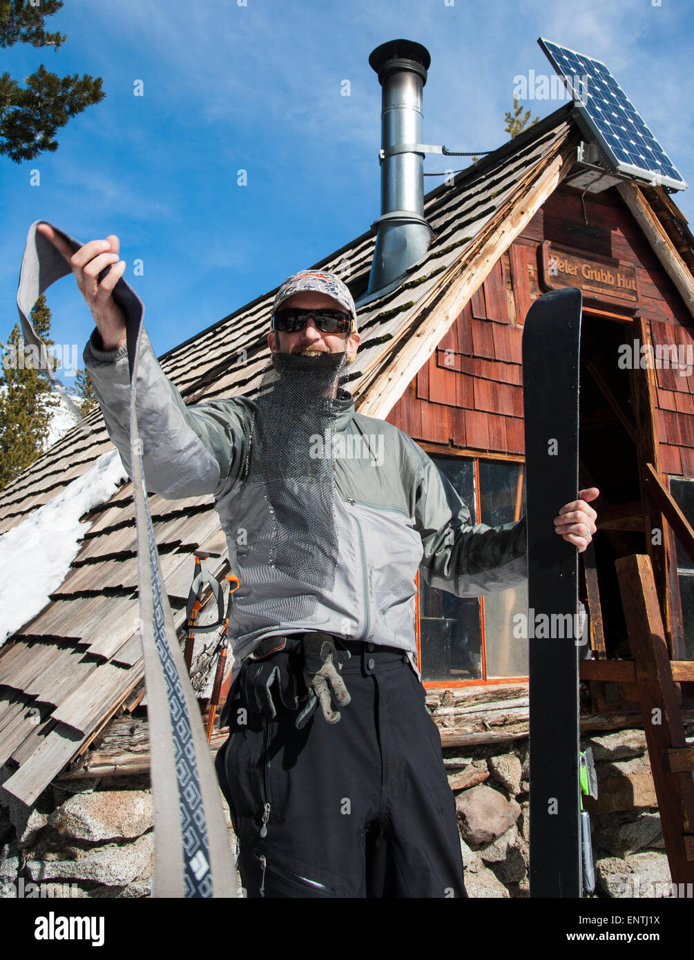 Skier putting climbing skins on skis in front of Peter Grubb Ski Hut