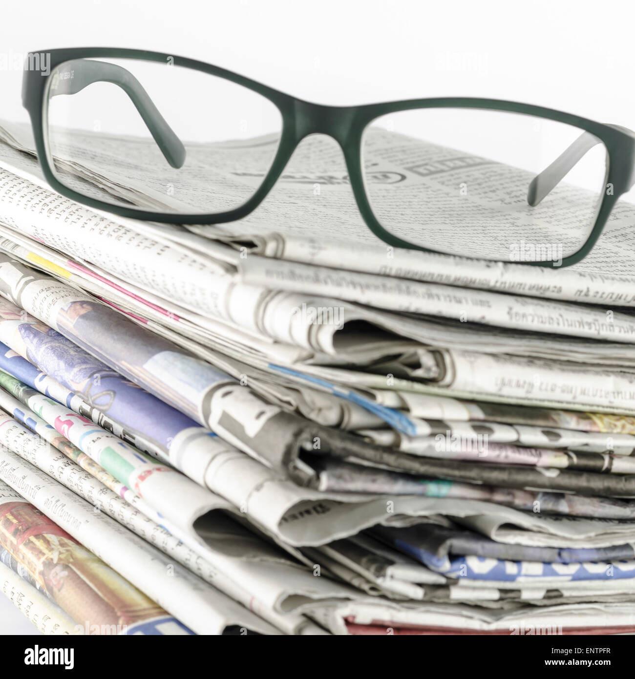 stack of newspaper with glasses on a white background Stock Photo