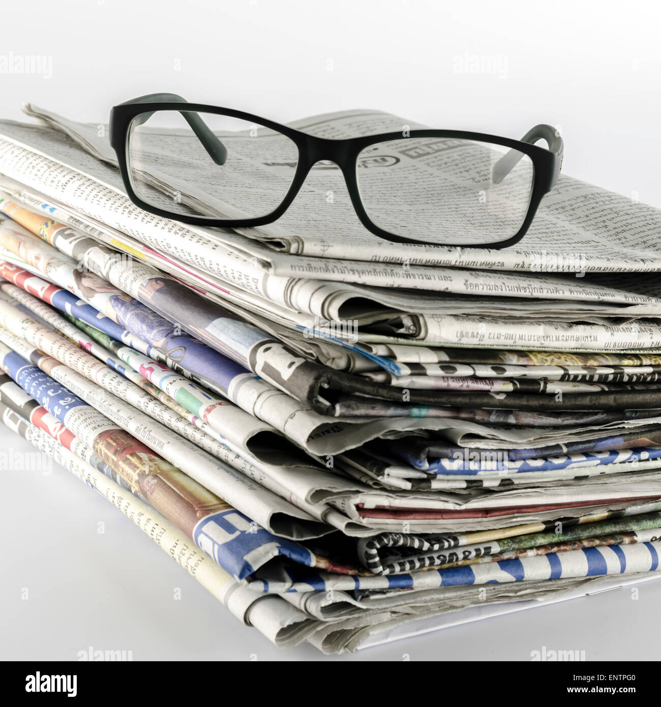 stack of newspaper with glasses on a white background Stock Photo