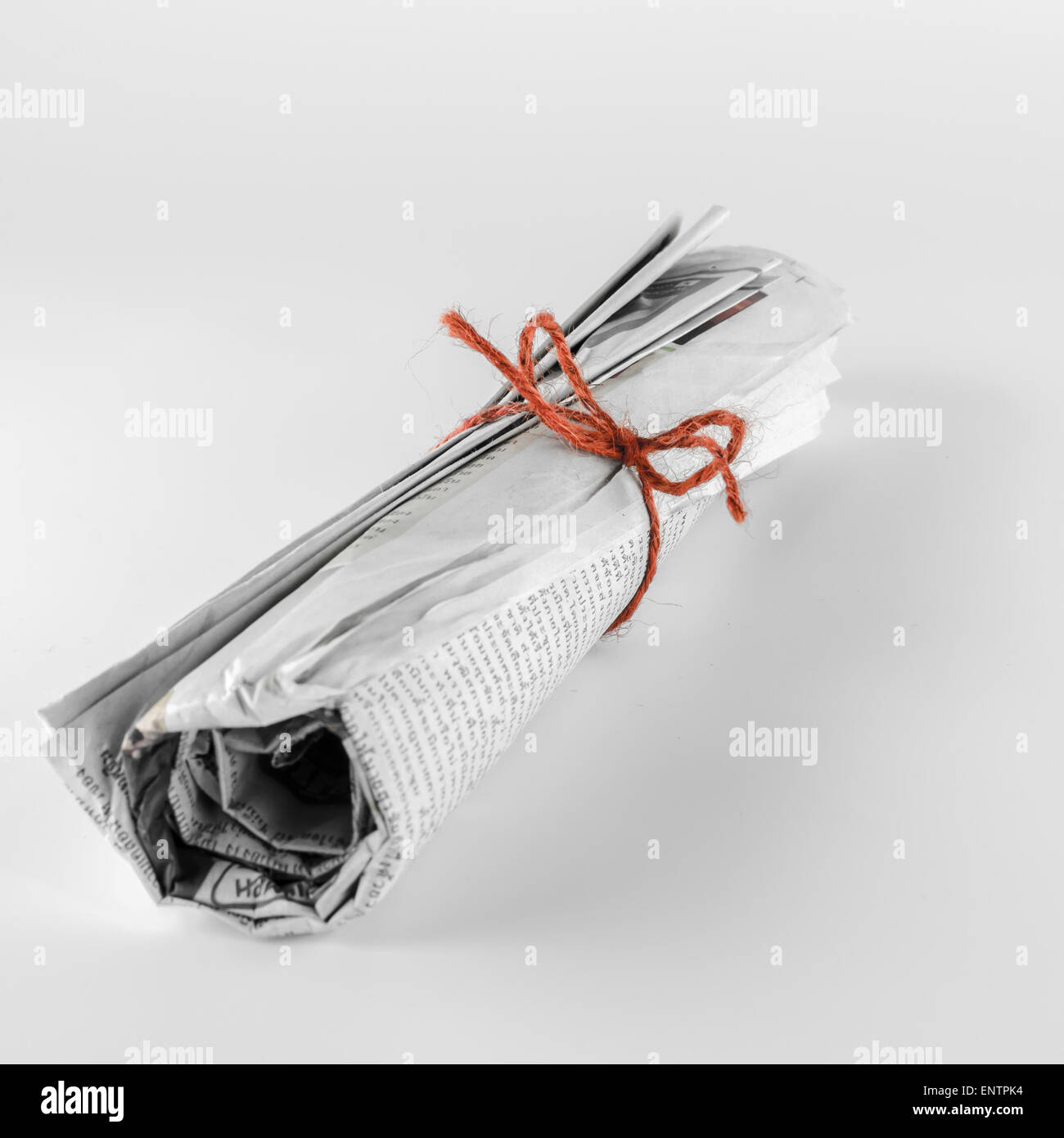 rolled up newspaper focus on red rope on a white background Stock Photo