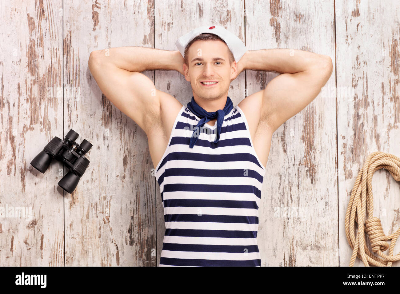 Young sailor lying on deck with a pair of binoculars beside him ...
