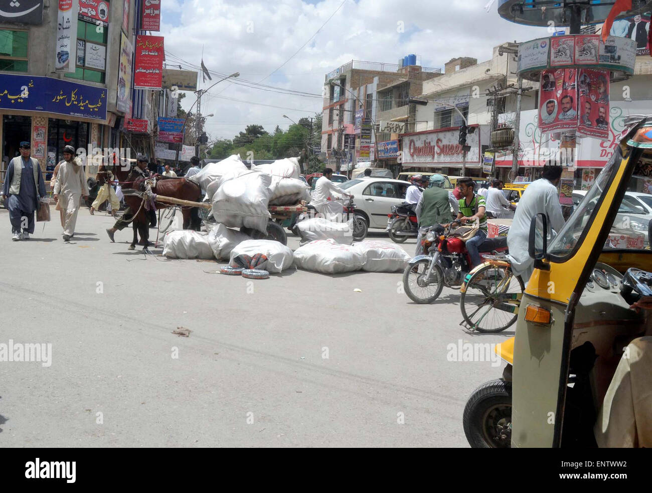 Commuters pass near a broken horsecart that damaged due to overloaded