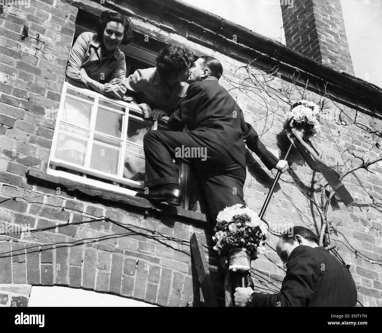 The tutti-men climb a ladder to get the traditional kiss the window during the Hock-tide festival at Hungerford. April 1955 P029159 Stock Photo
