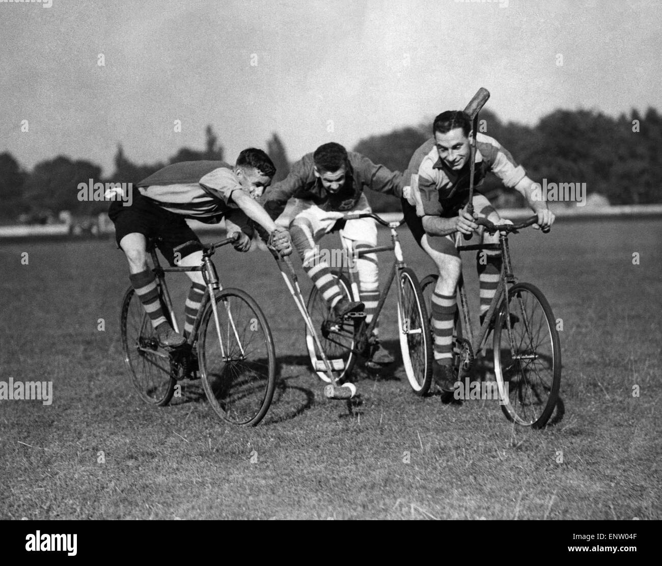 Three fellows playing Cycle polo which was invented in County Wicklow, Ireland, in 1891 by retired cyclist, Richard J. Mecredy. The sport is similar to traditional polo, except that bicycles are used instead of horses. 13th June 1937 Stock Photo