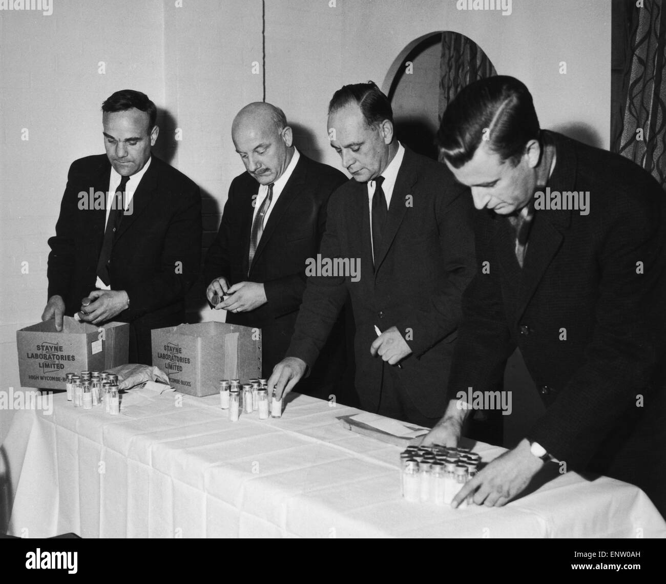 Police investigation into the murder of 17 year old nanny Yolande Waddington, who was found strangled in Beenham, Berkshire, in October 1966. Yolande had been stabbed and strangled. The 200 men and boys aged between 16 & 50 who live in Beenham have been asked to volunteer samples of their blood. Pictured: Policemen arranging sample bottles in the village hall. From left to right Sergeant Boff, Superintendent Virgo, Superintendent Lawson and Police Constable Swanborough. 24th November 1966 Stock Photo