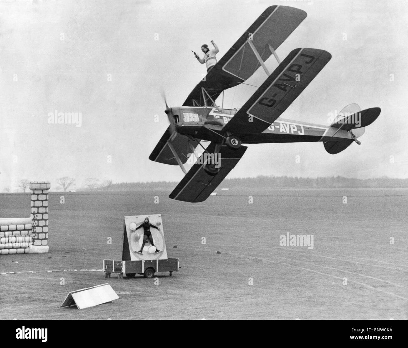 Graham Tyson on the wings of the Tiger moth with a Colt 38 ready to shoot from a moving aircraft at the balloons surrounding his fiancee, Christine Good. 17th April 1977 Stock Photo