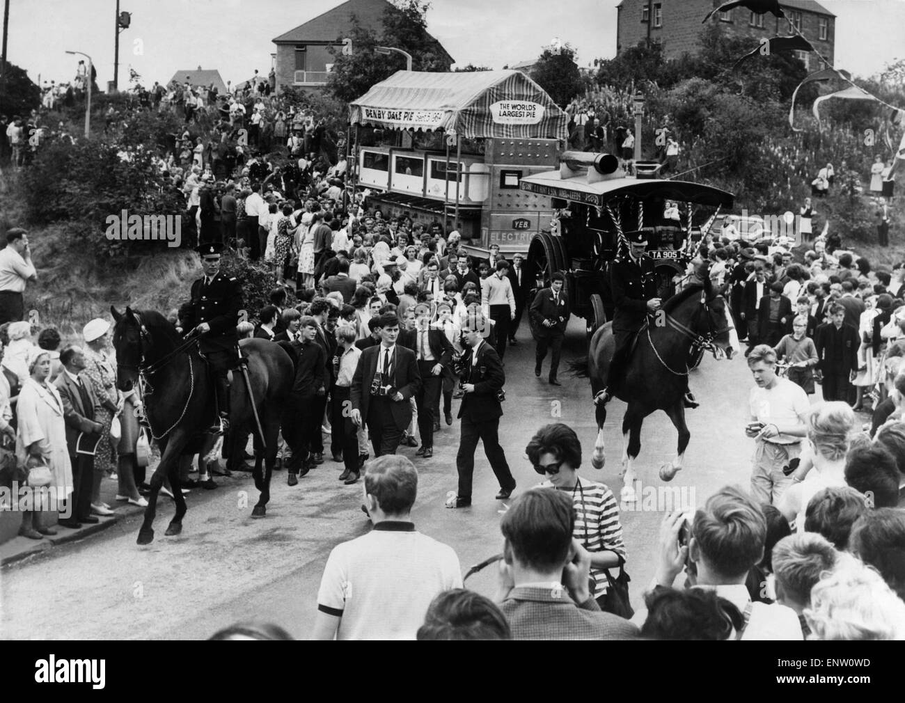 Cheering crowds greet the Denby Dale Pie, escorted by two mounted