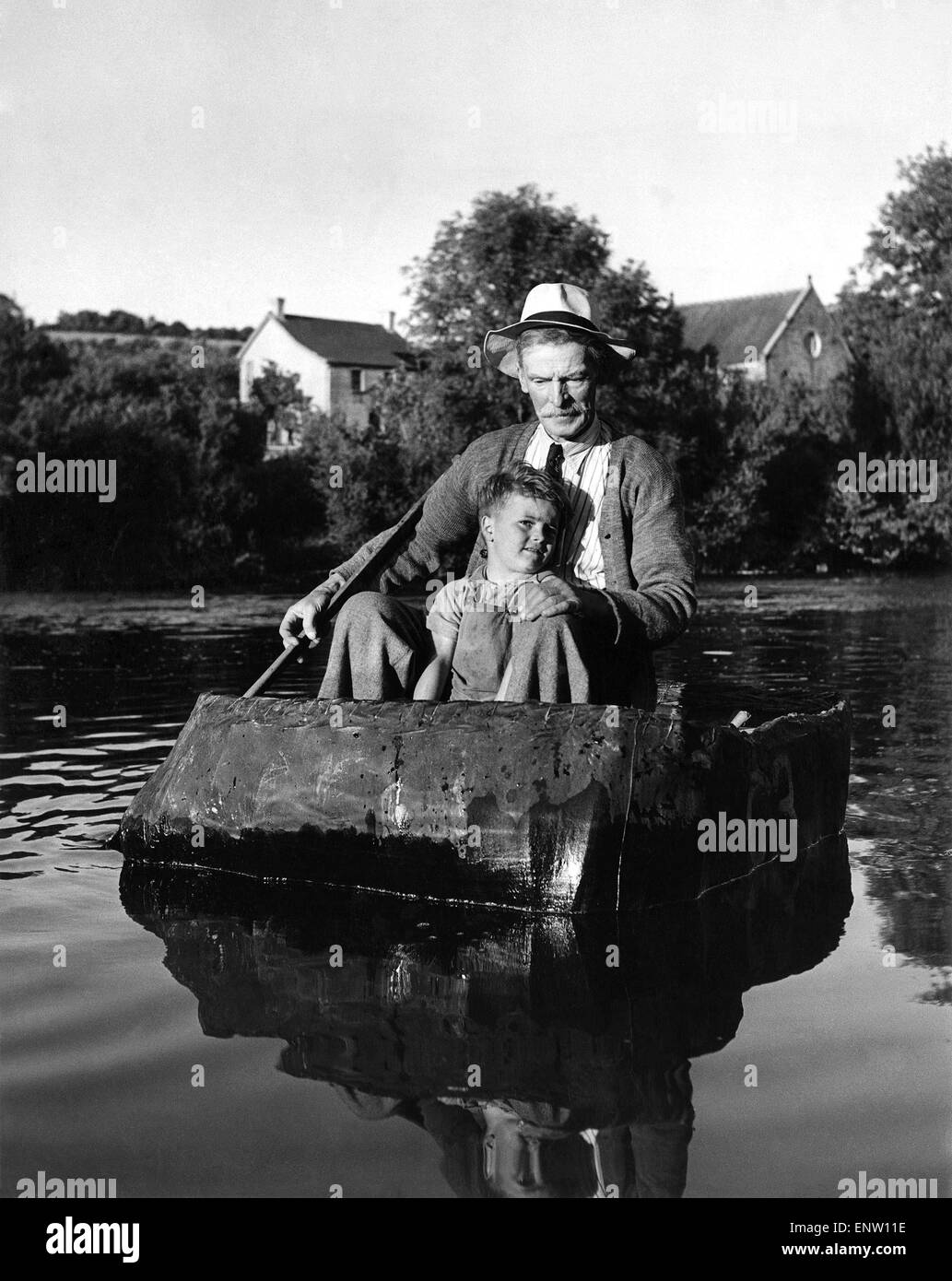William David Owen is 72 years of age. For thirty years he's been coracle fishing. Now, as he paddles four-year-old Alan Davies across the Teify, he becomes deep in thought. His is a dying industry and young Alan must look elsewhere for work. Circa 1939 Stock Photo