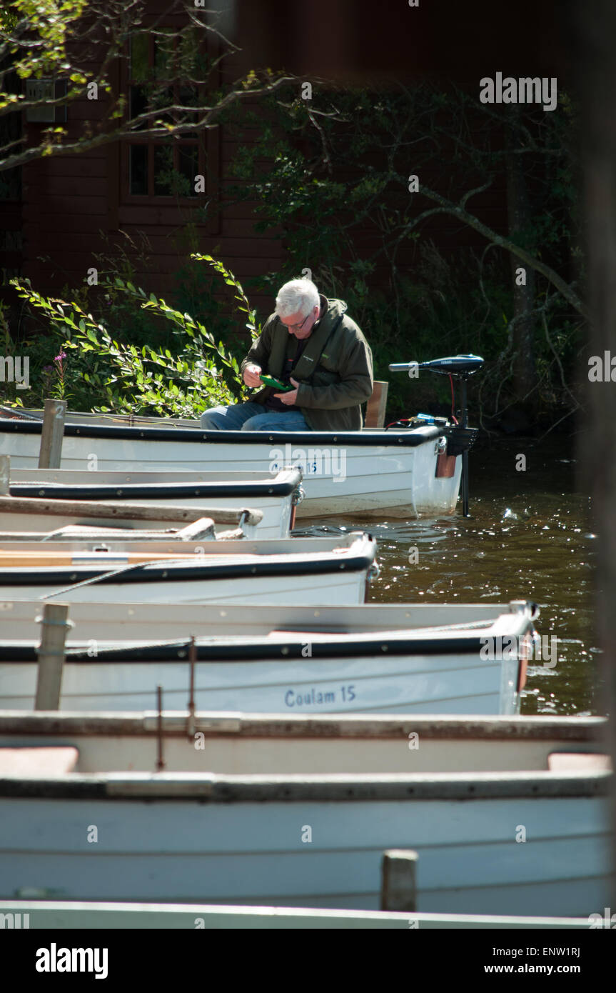 Fisherman on his boat preparing his gear to go fishing on one of the reservoirs around Edinburgh, Scotland Stock Photo