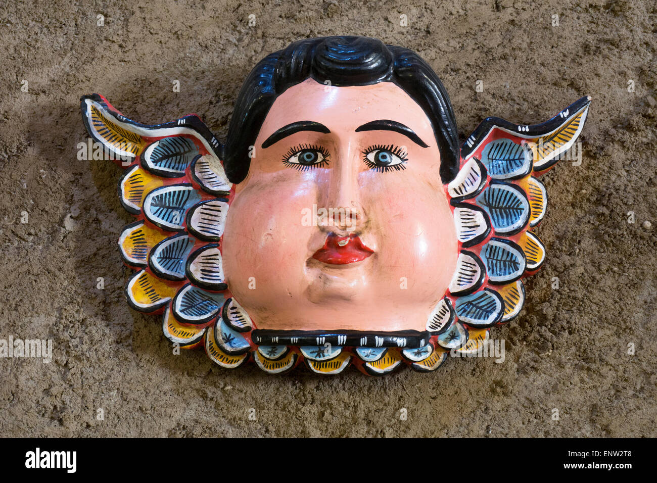 sweet contemporary folk art plaster angel with blue eyes plump cheeks & colorful wings decorates restaurant wall San Cristobal Stock Photo