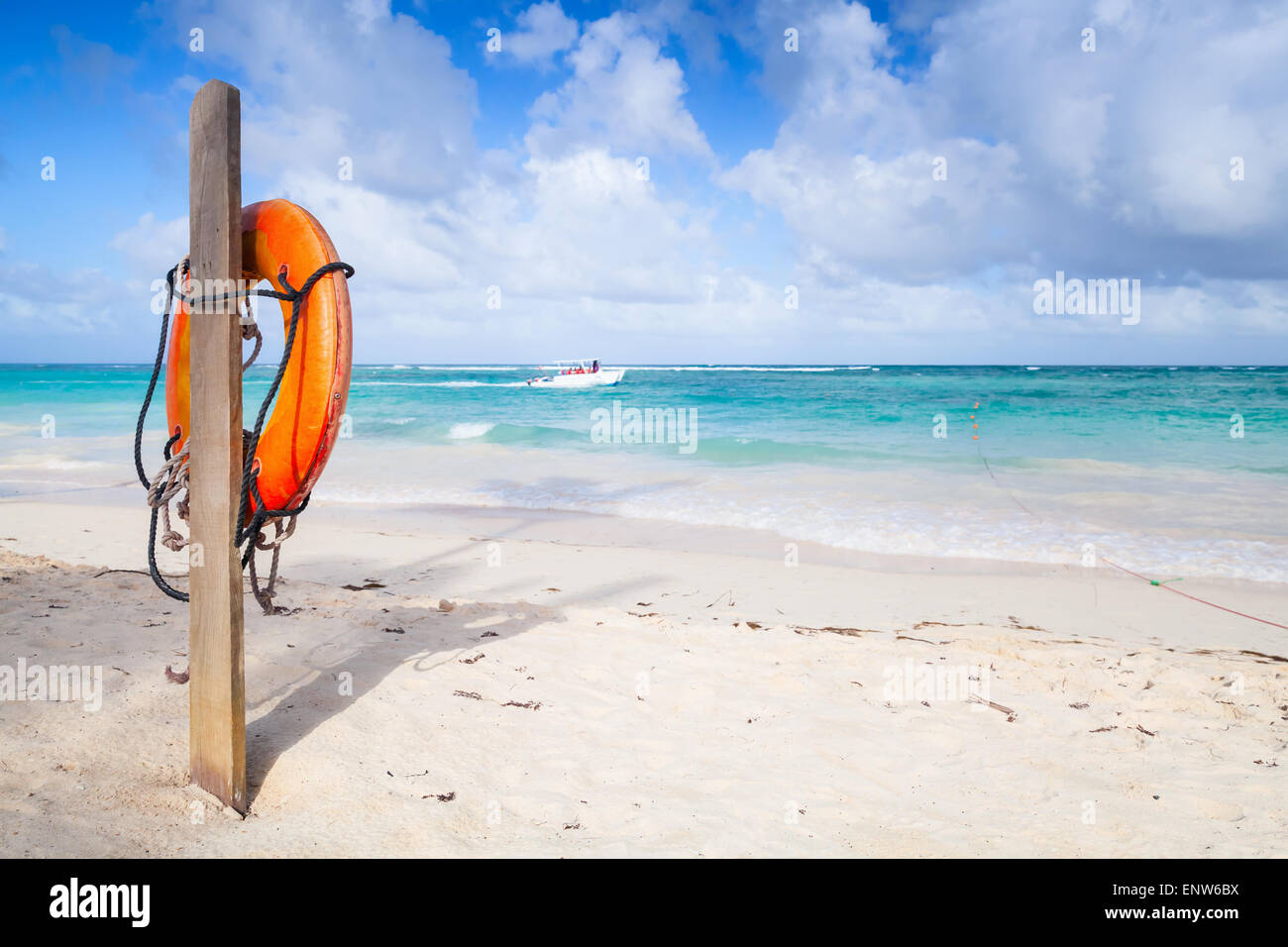 Red round life buoy hanging on wooden pole, empty sandy beach of Dominican republic Stock Photo