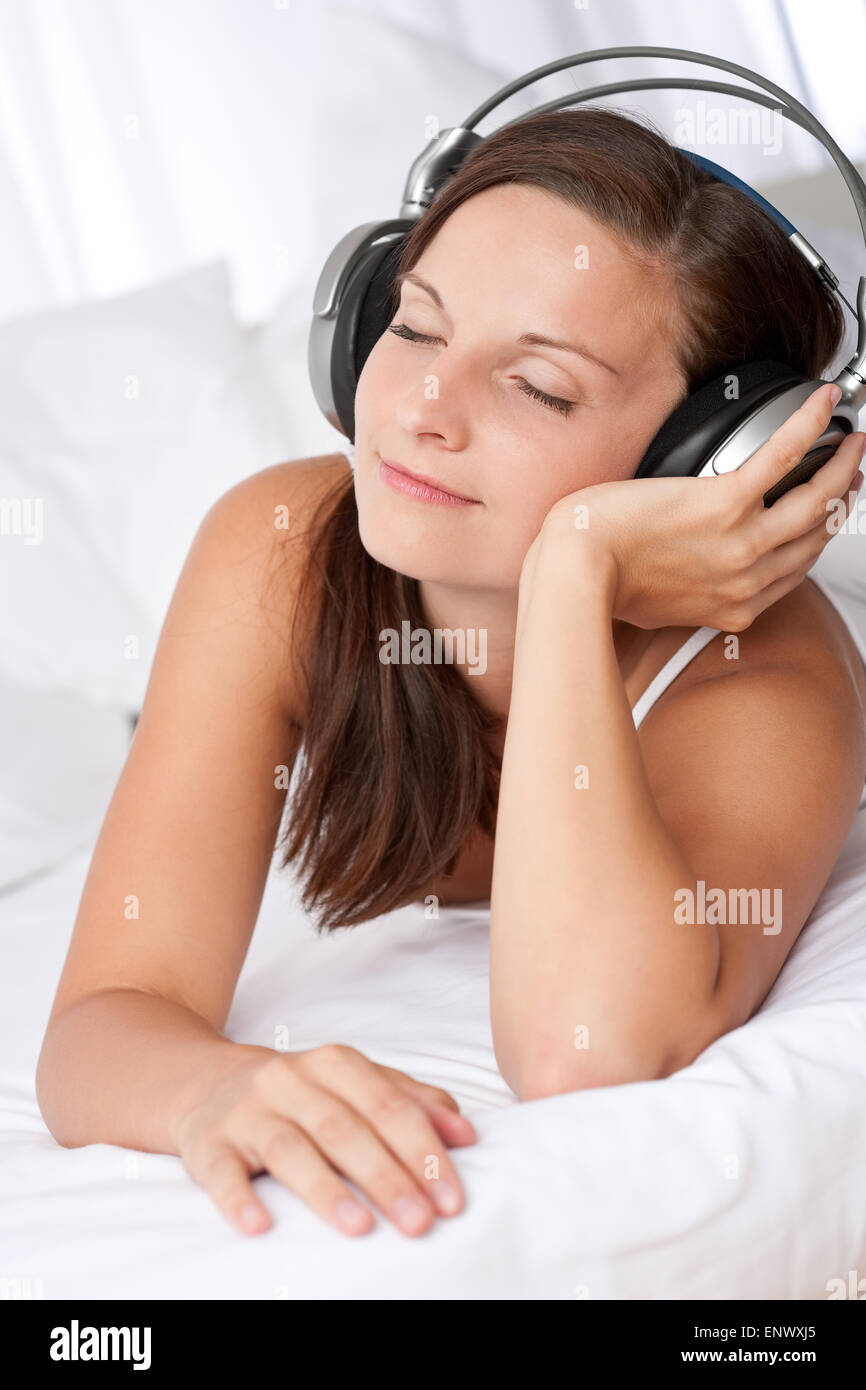 Happy woman lying on white sofa listening to music Stock Photo - Alamy