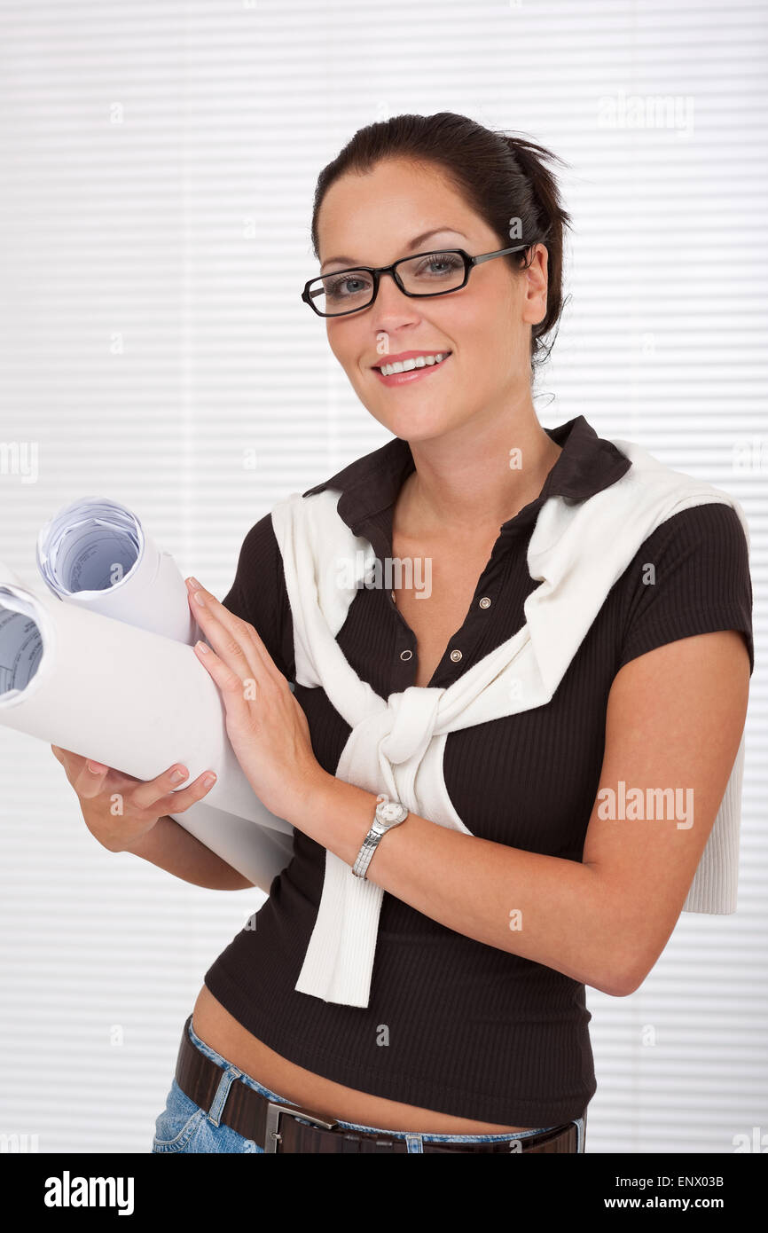 Smiling female architect with glasses holding plans Stock Photo - Alamy