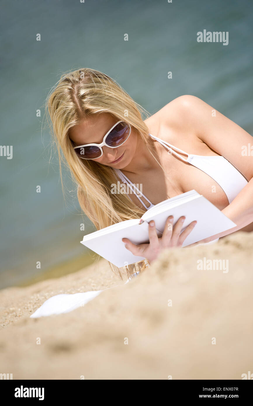 Blond woman in bikini relax on beach with book Stock Photo