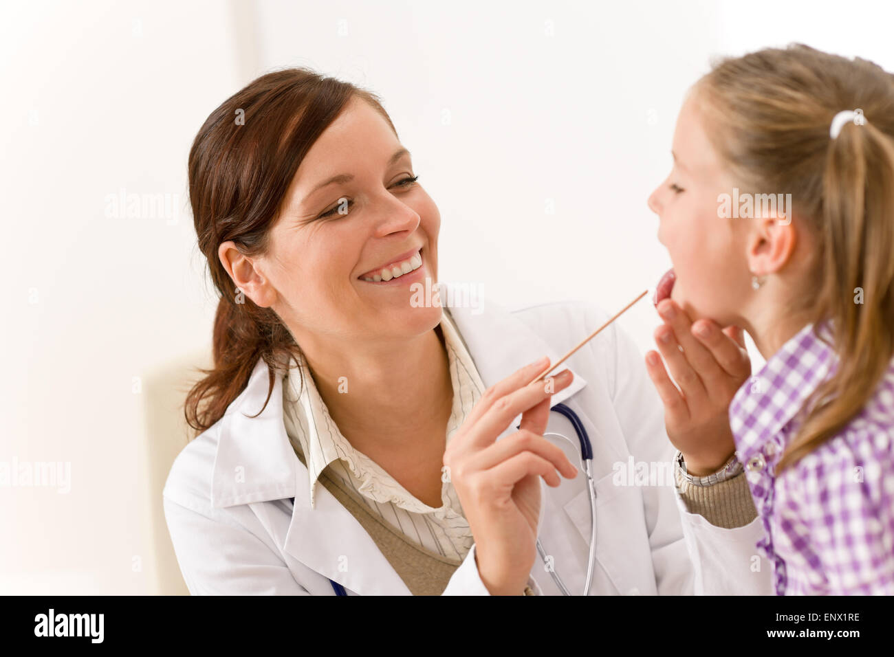 Female doctor examining child with tongue depressor Stock Photo Alamy