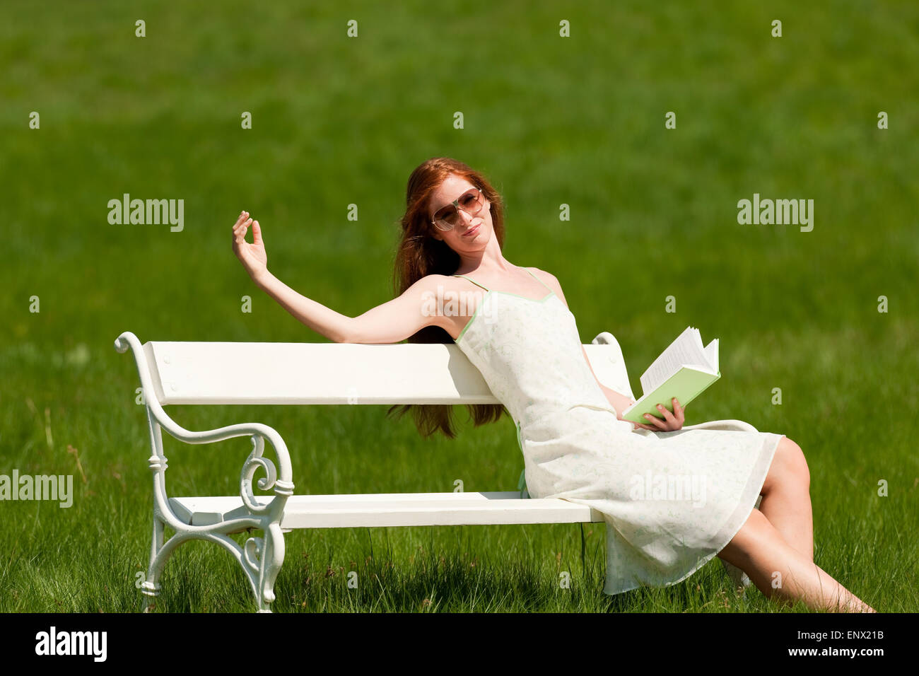 Red hair woman sitting on white bench in spring Stock Photo - Alamy