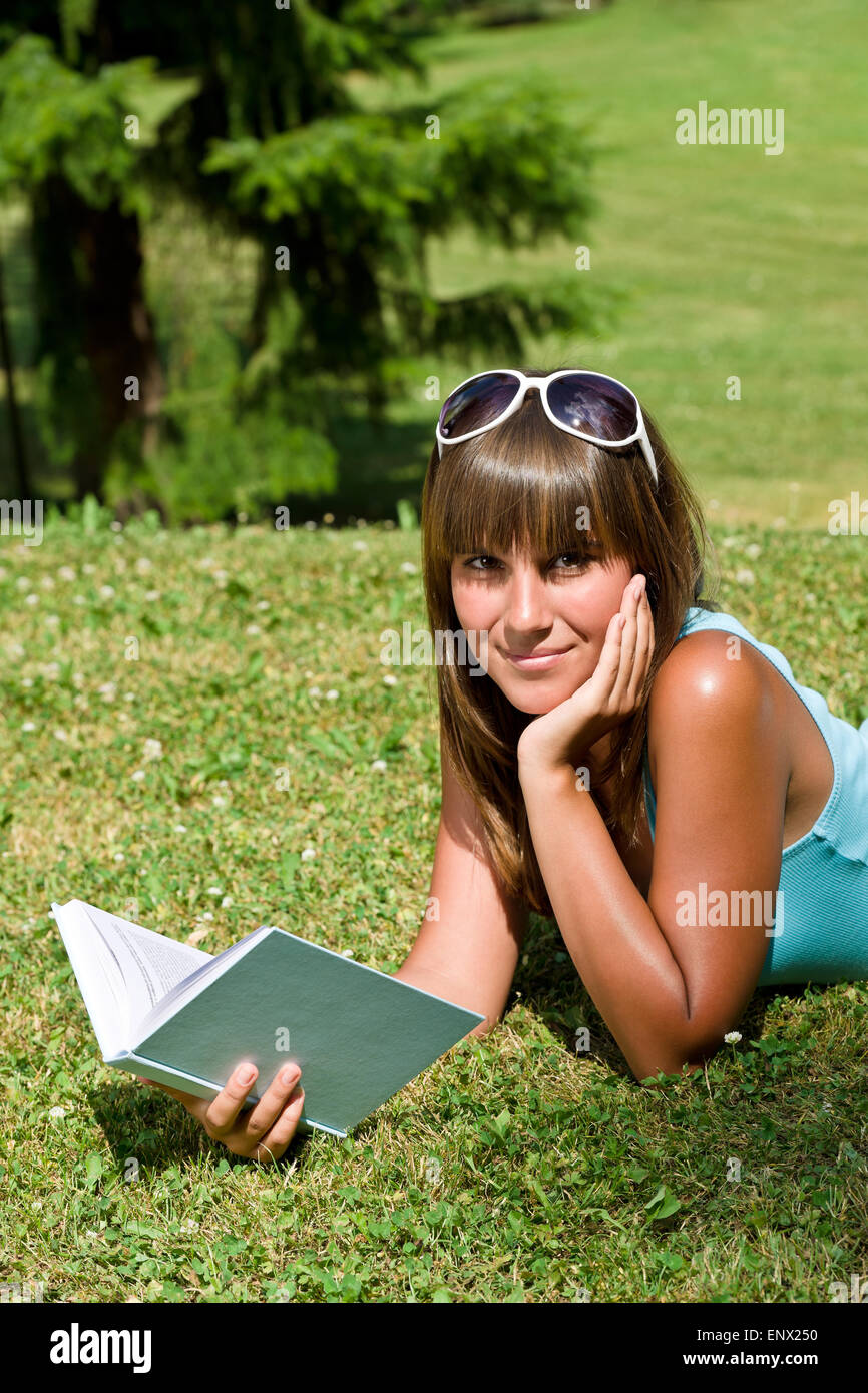 Smiling young woman lying down on grass with book Stock Photo - Alamy