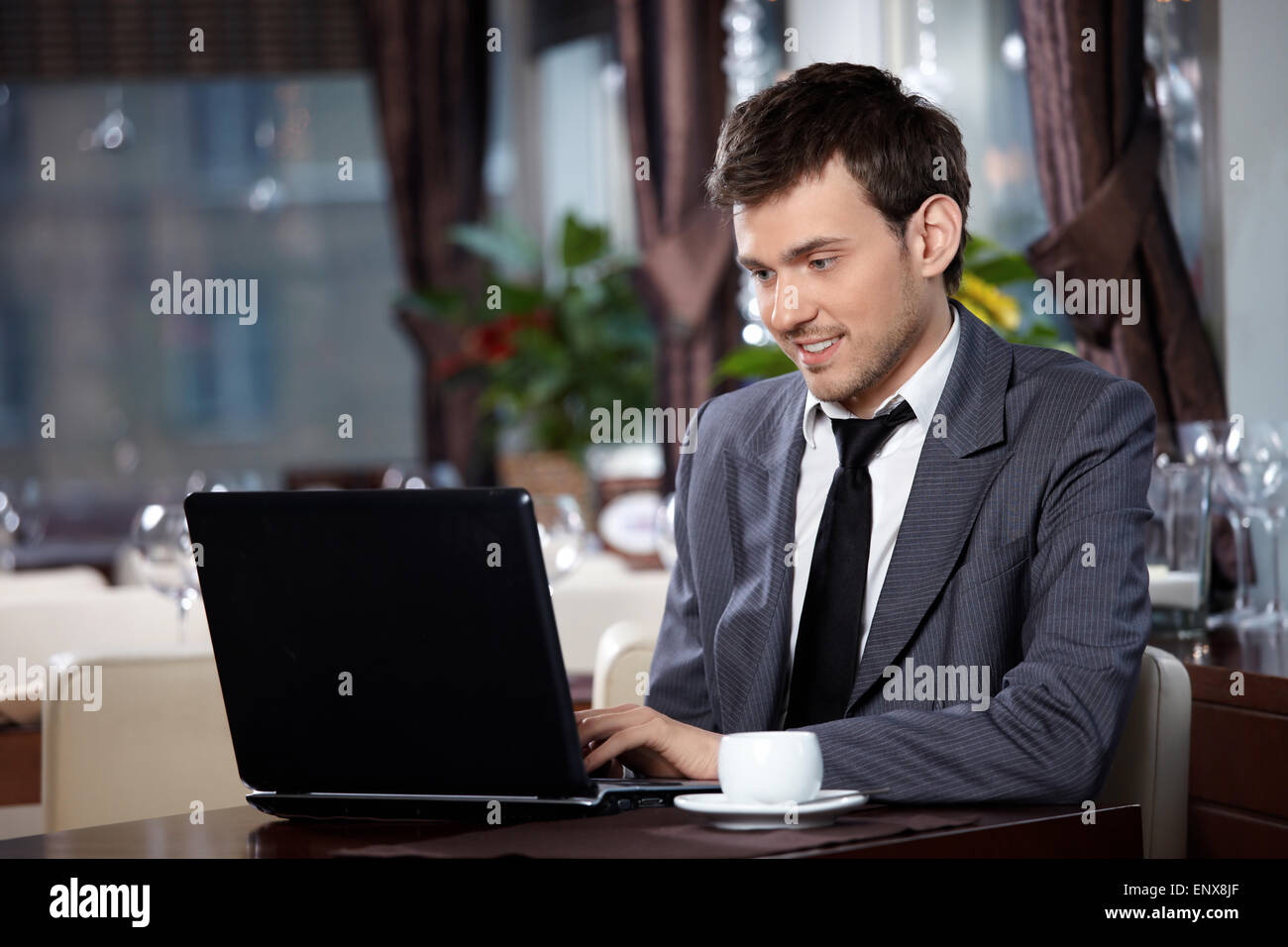 Business man with the laptop sits at a table in cafe Stock Photo