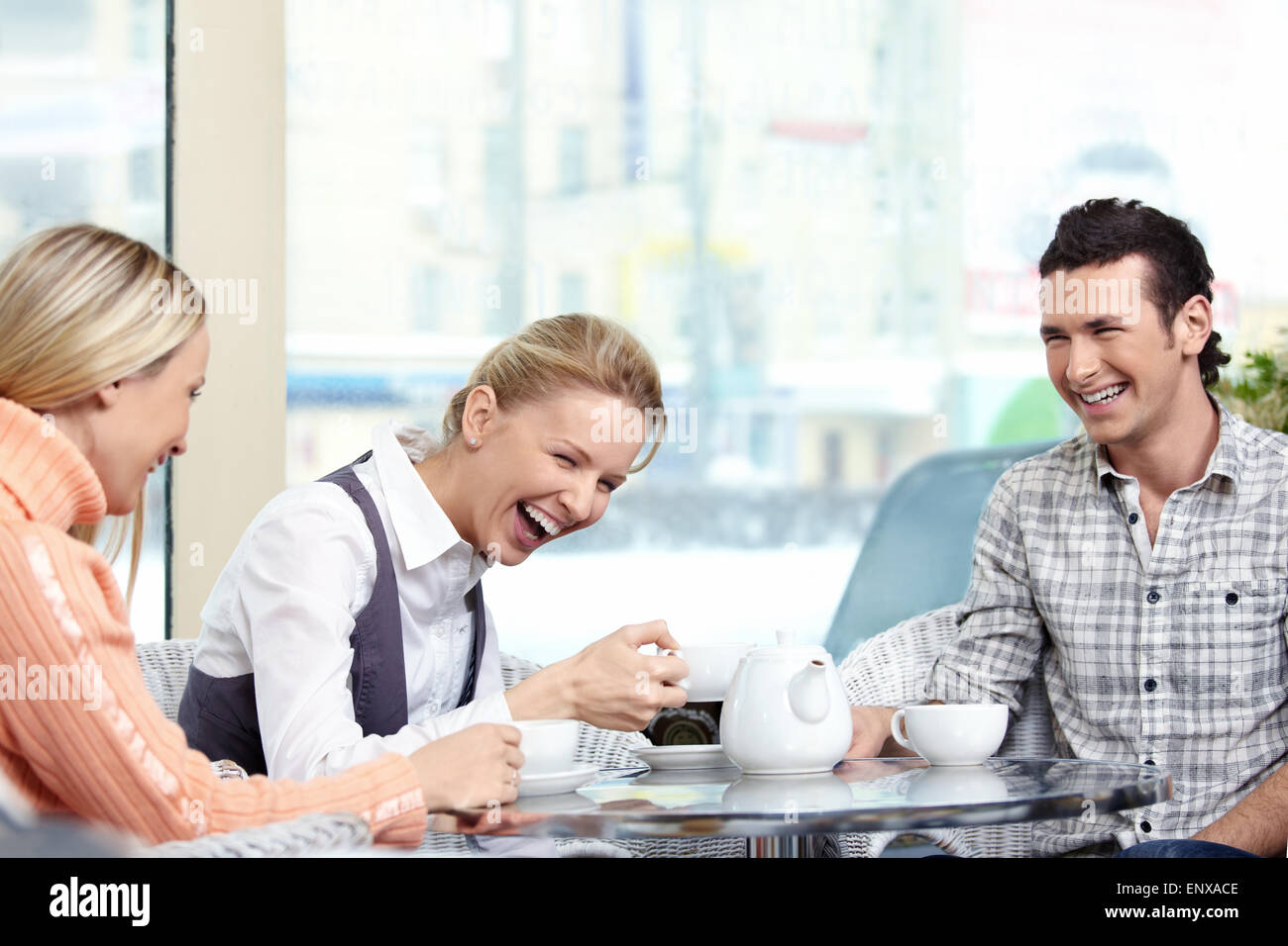 Young men behind a table in the foreground laugh Stock Photo