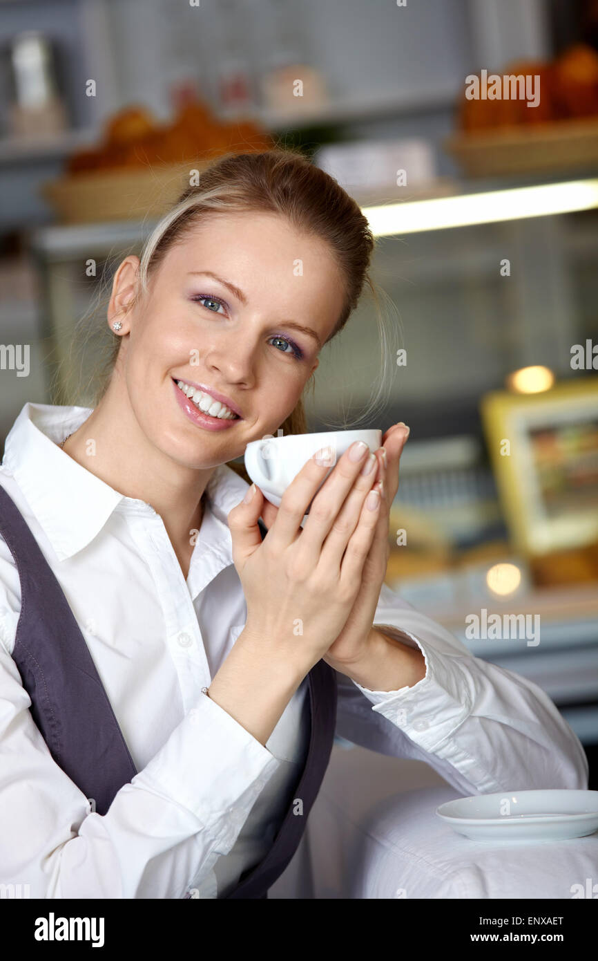 The beautiful girl with a cup in the foreground in cafe Stock Photo