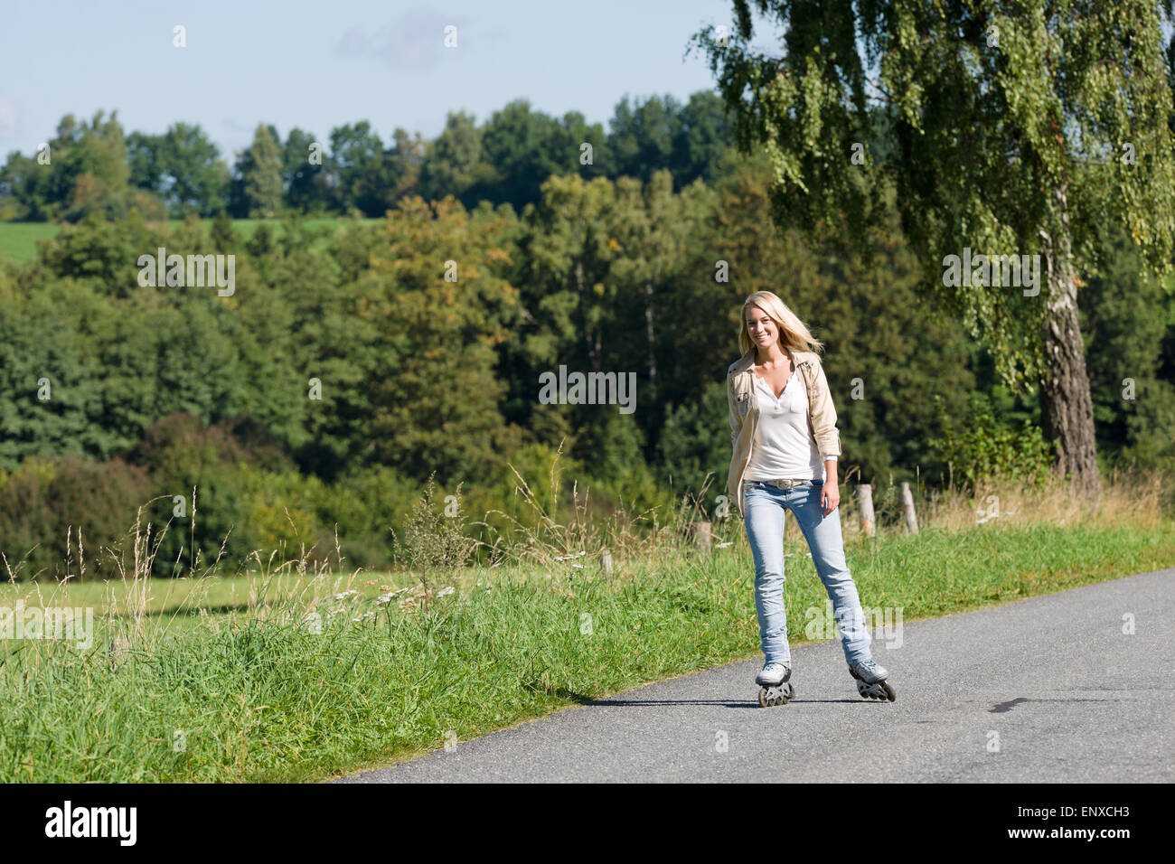 Inline skating young woman on sunny asphalt road Stock Photo Alamy
