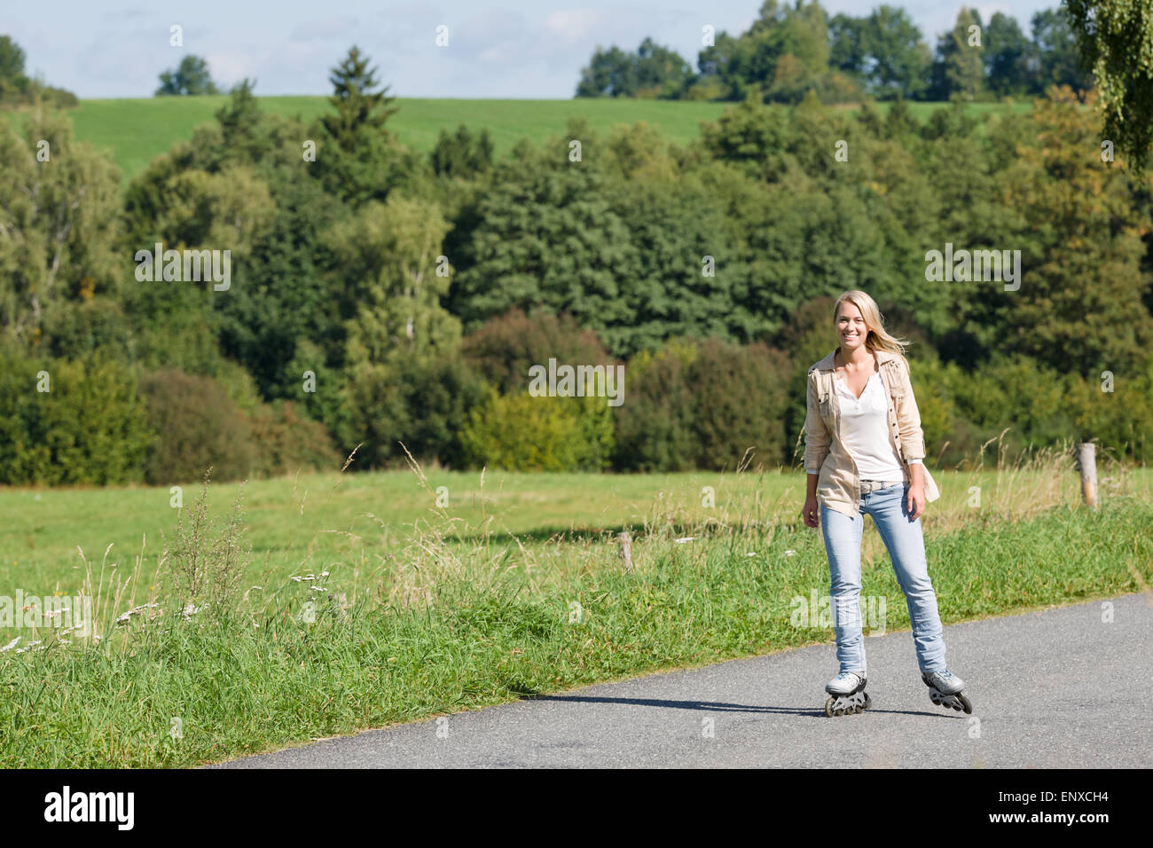 Inline skating young woman on sunny asphalt road Stock Photo Alamy