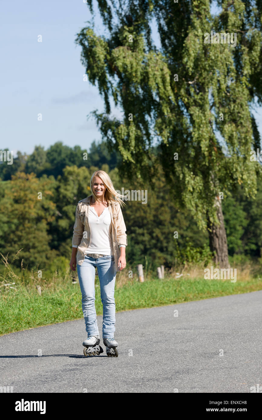 Inline skating young woman on sunny asphalt road Stock Photo Alamy