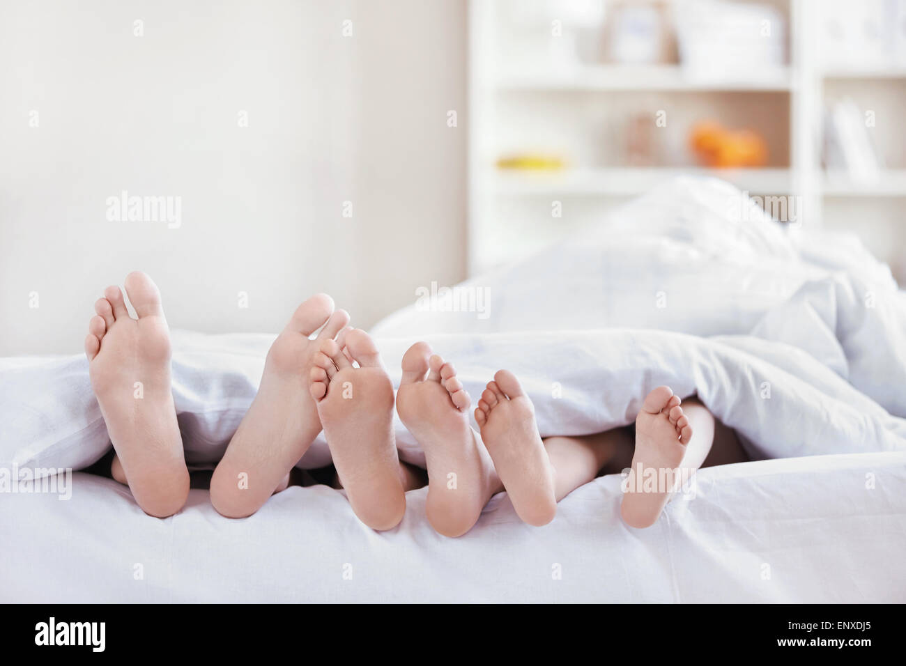 Legs sticking out from under the blankets in the bedroom Stock Photo