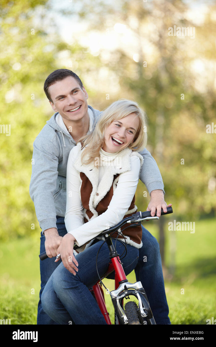 Laughing couple on a bike in the autumn park Stock Photo