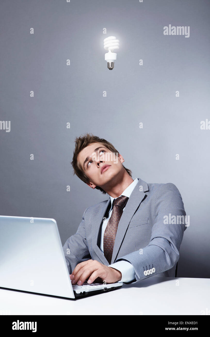 Young businessman in a suit looks at a burning light bulb Stock Photo
