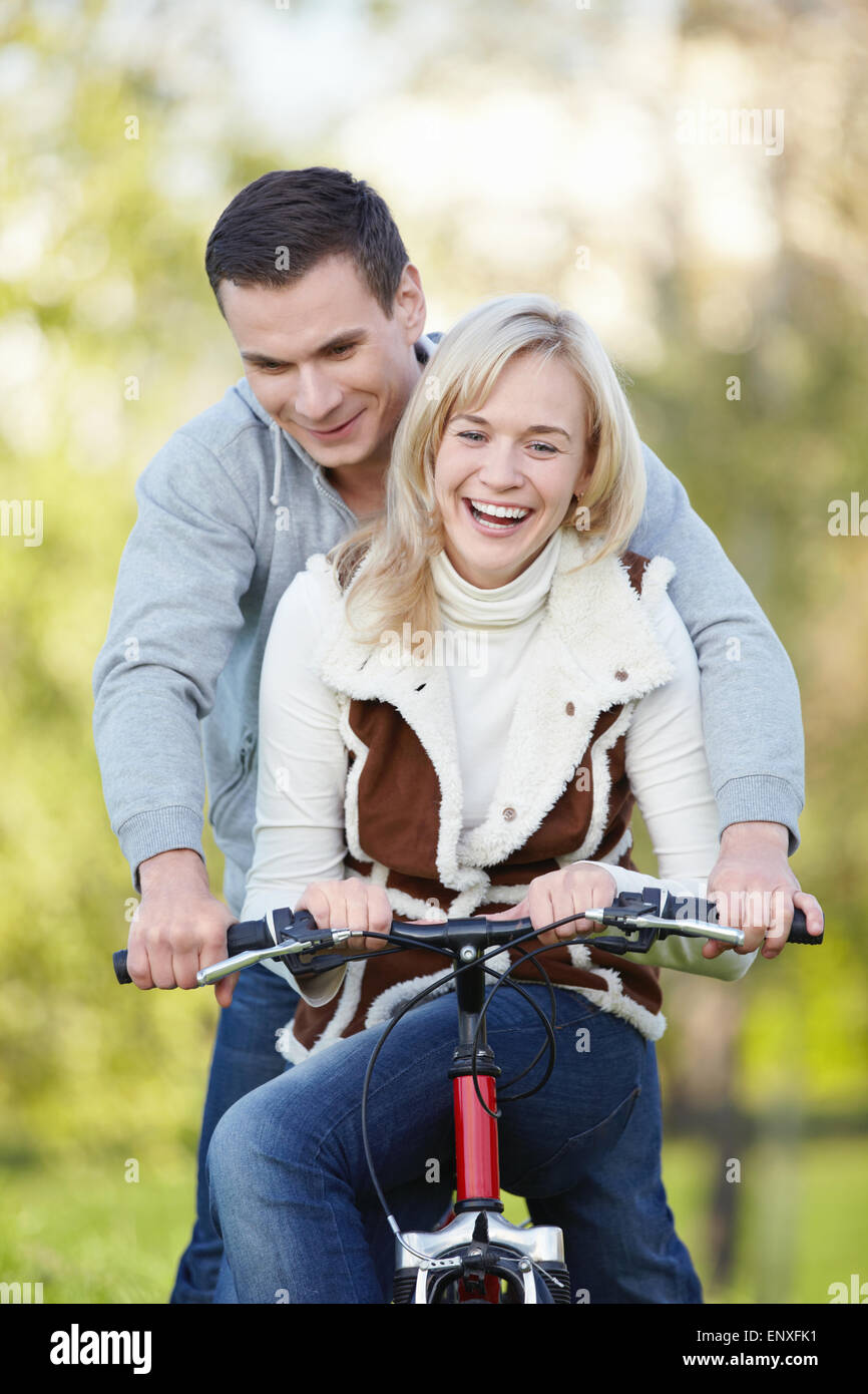 Young attractive couple rides a bicycle in the park Stock Photo