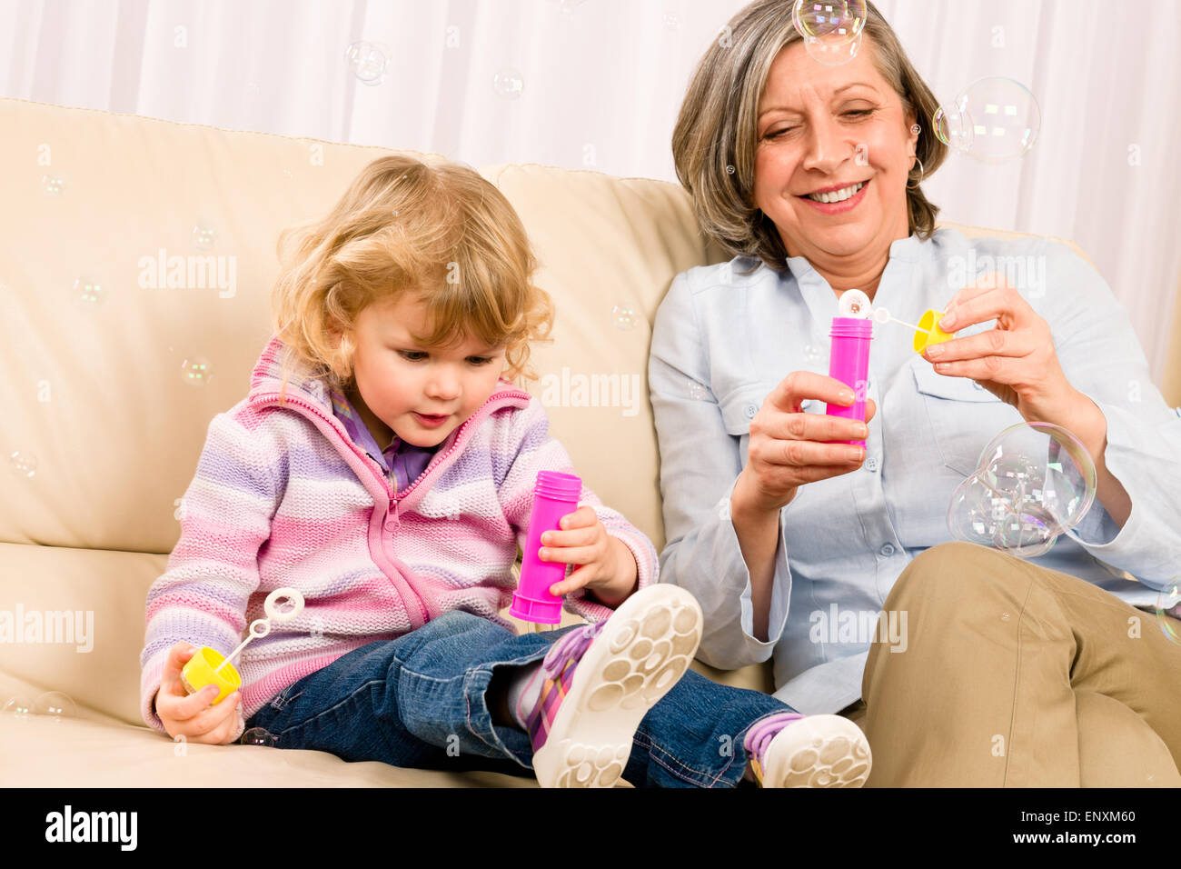 Little girl with grandmother play bubble blower Stock Photo - Alamy