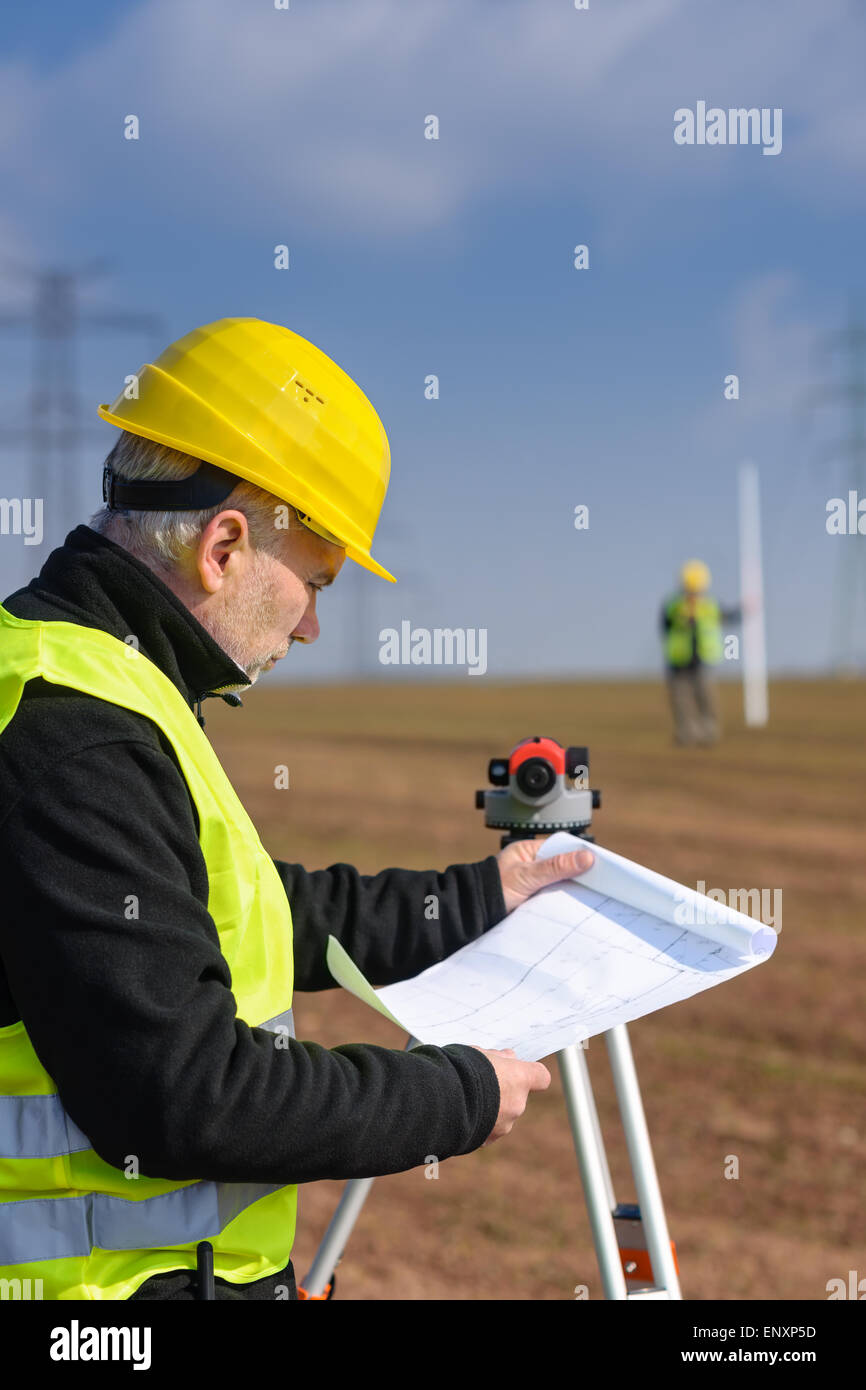 Geodesist male look land plans measure theodolite Stock Photo - Alamy
