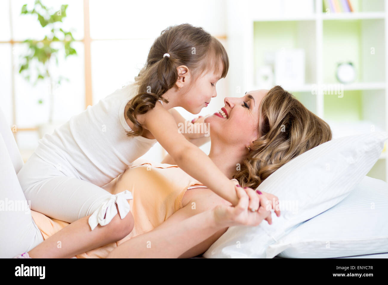 Mom and child daughter embracing and kissing in bed Stock Photo