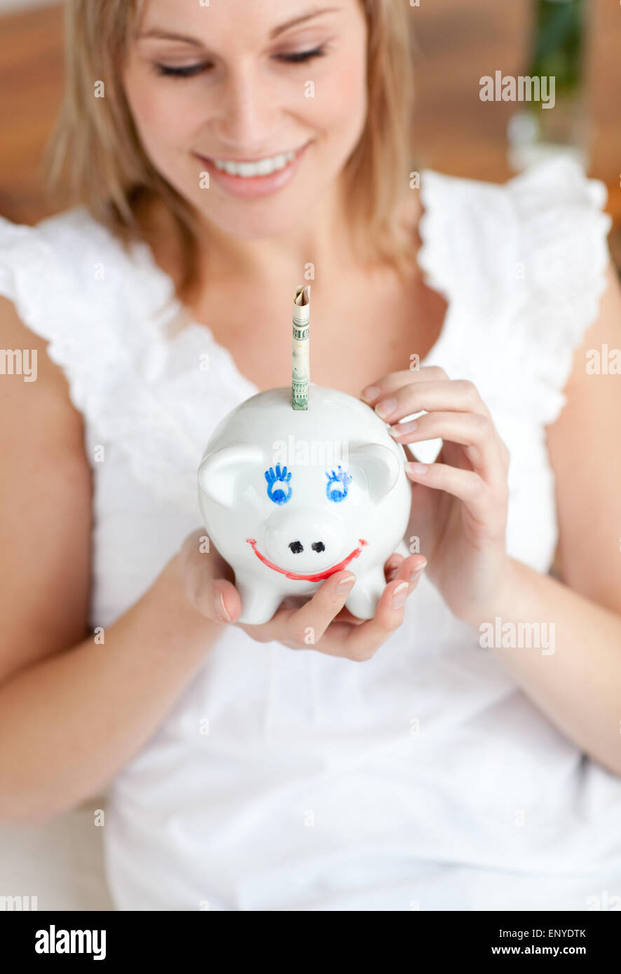 Charming woman saving money in a piggy-bank Stock Photo - Alamy