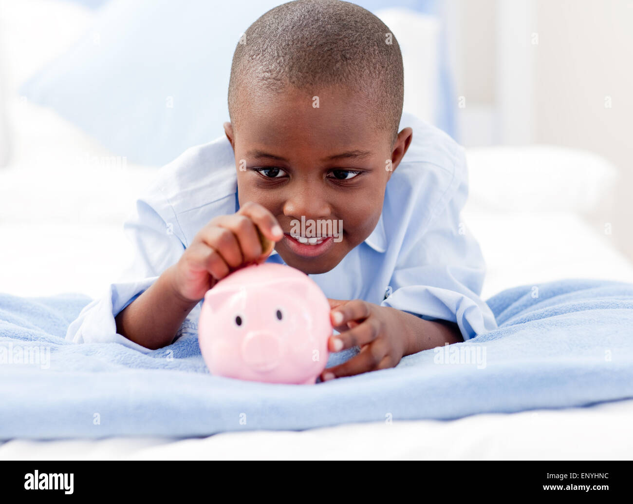 Young Boy on a bed putting money into a piggy bank Stock Photo - Alamy