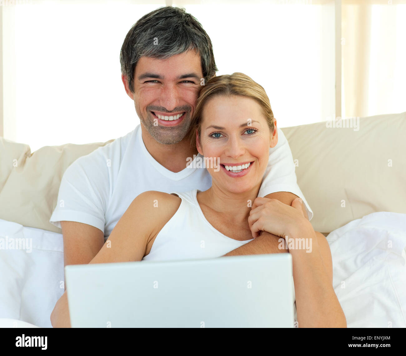 Smiling couple using a laptop lying in the bed Stock Photo - Alamy