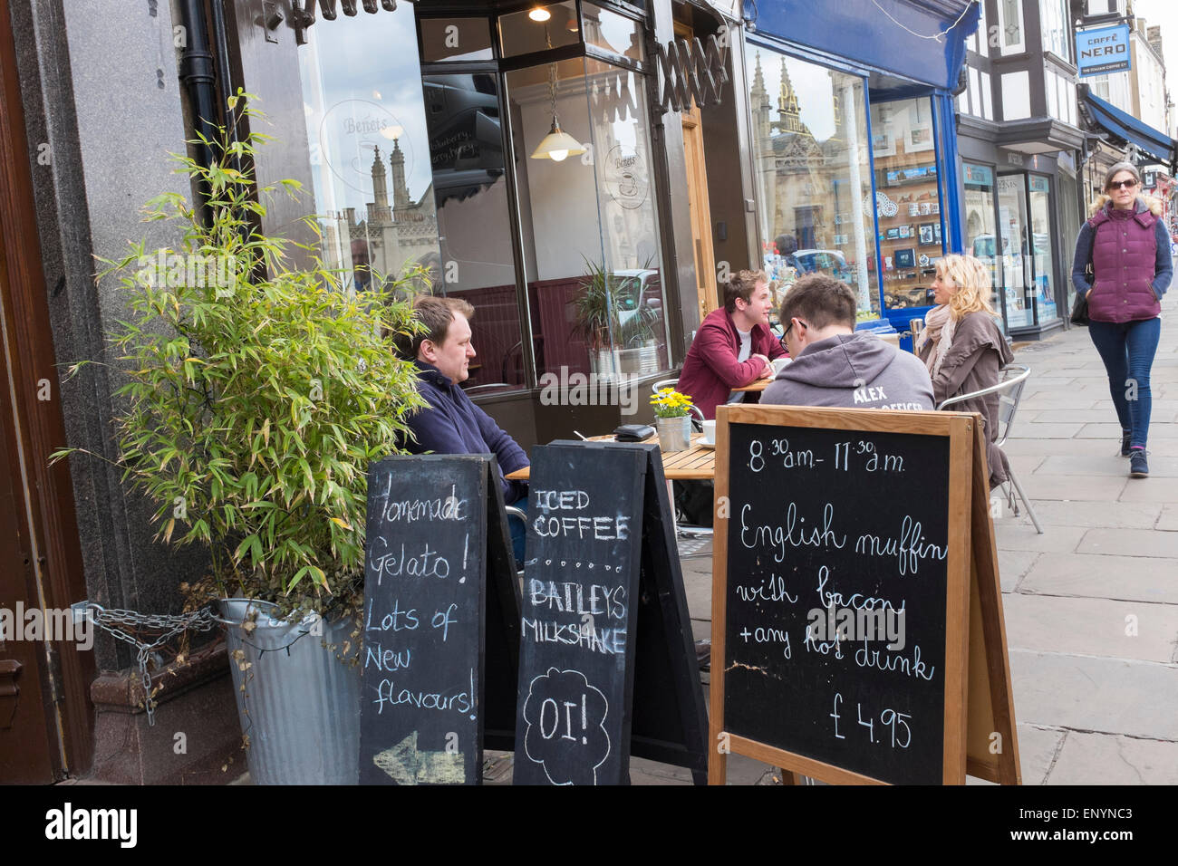 People sat at tables eating drinking talking outside Benet's coffee shop King's Parade Cambridge city England Stock Photo