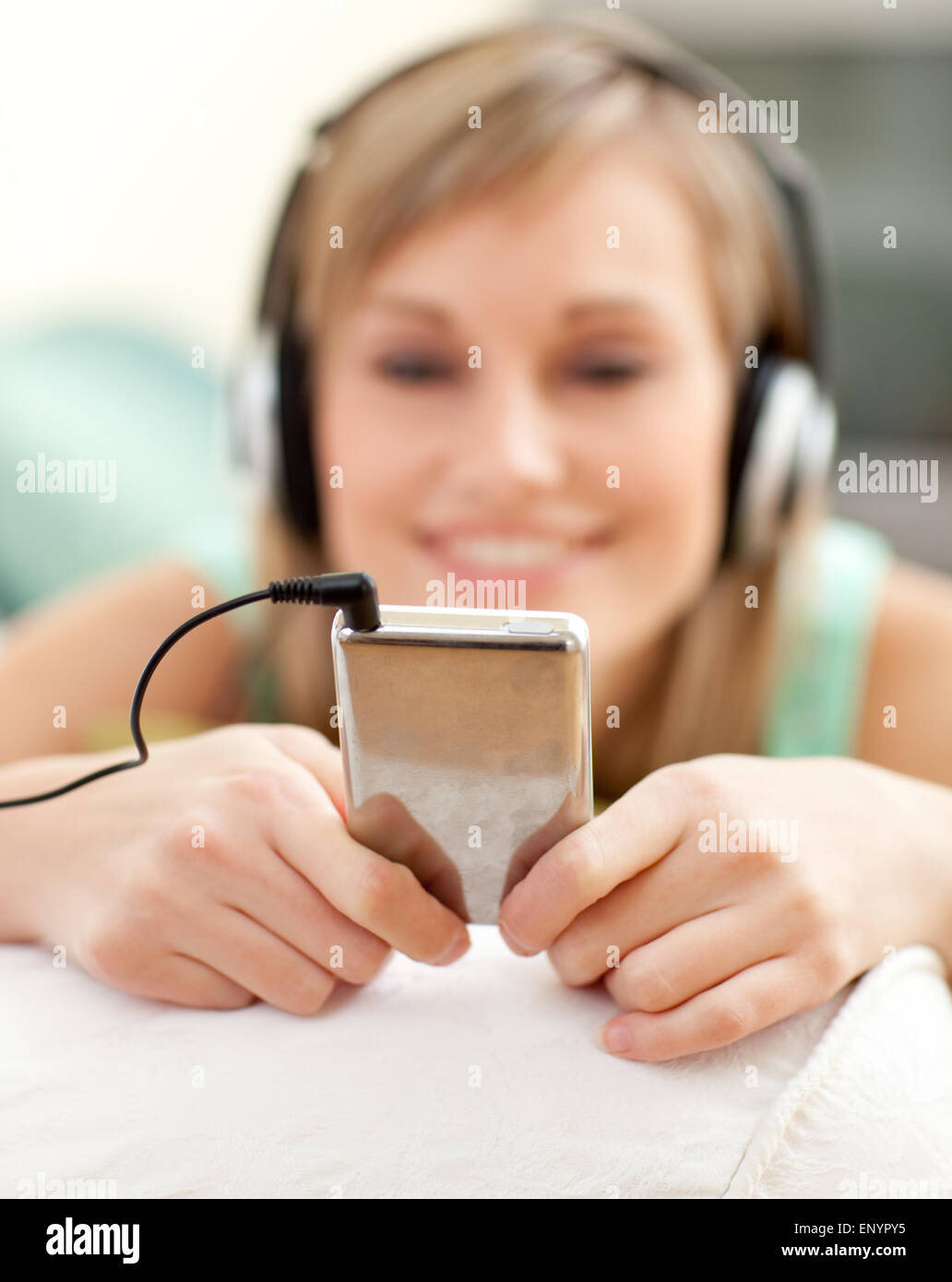 Young blond woman listening music lying on a sofa Stock Photo - Alamy