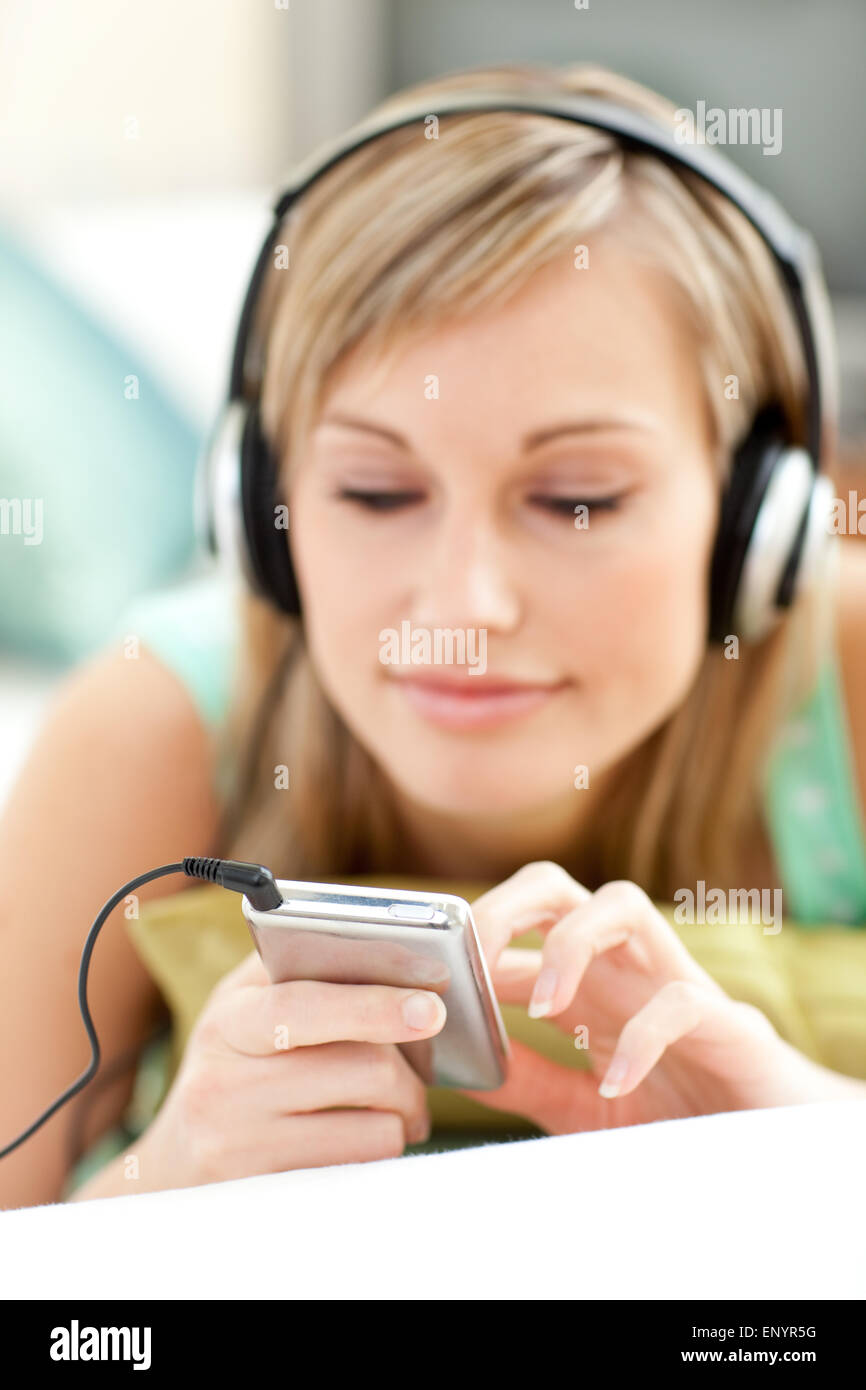 Pretty young woman listening music lying on a sofa Stock Photo - Alamy